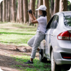 A person leans against their vehicle and uses a camera to take photos of the forest. 
